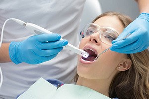 young girl in dental chair with protective glasses and dentist using SOPROCARE® intraoral camera